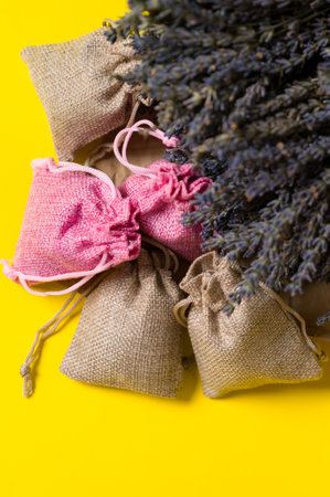 Dried lavender flowers and sachets on yellow background, lavender aromatherapy.の写真素材