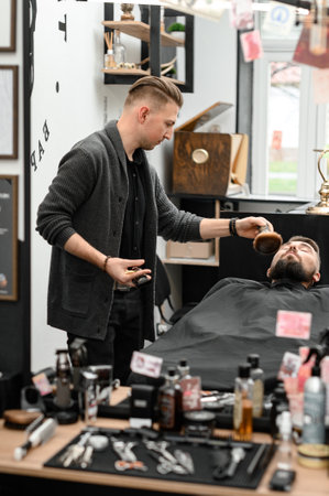 Cutting a gentleman beard in a barbershop with a clipper. Shortening the length of the beard from the sides by the master for the client.の写真素材