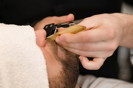 A barber trims a Caucasian client mustache with a trimmer.の写真素材