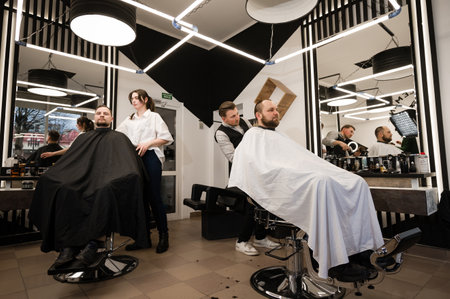 Ivano-Frankivsk, Ukraine, February 23, 2024: work in a barbershop, young barbers cut customers hair.のeditorial素材