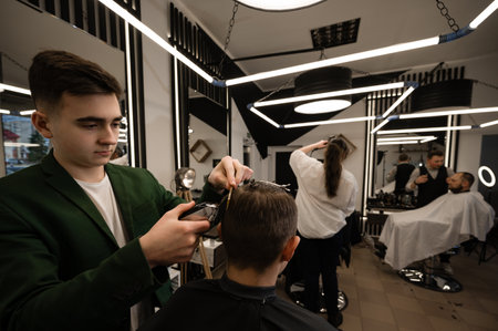 Ivano-Frankivsk, Ukraine February 23, 2024: A young barber cuts a boys hair.のeditorial素材