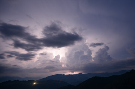 An evening thunderstorm with lightning in the Carpathian mountains, the village of Dzembronya. Dramatic clouds during a thunderstorm pierce the light of lightning in a mountainous area.の写真素材