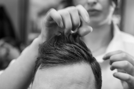 Hair styling with a hand, combing the client's hair by a stylist. Haircut of a visitor in a barbershop.の写真素材