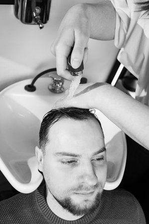 Barber shampooing washing a male client's head in the sink.の写真素材