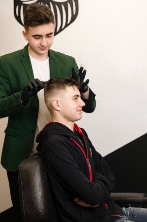 Hair styling with a hand, combing the client's hair by a stylist. Haircut of a visitor in a barbershop.の写真素材