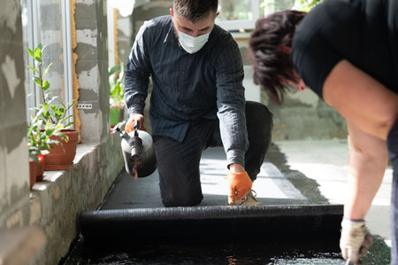 A man and a woman are engaged in waterproofing the floor of the house, repair and construction work.の写真素材