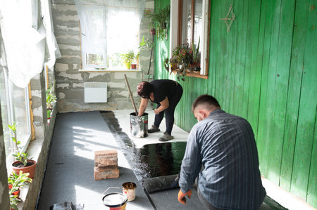 A man and a woman are engaged in waterproofing the floor of the house, repair and construction work.の写真素材