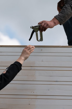 Workers hand staplers to each other at a construction site.の写真素材