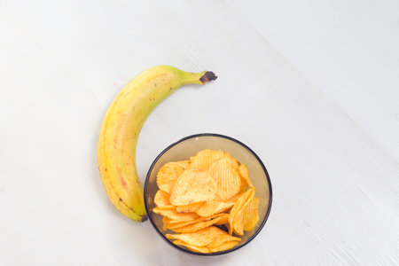 Banana and potato chips on a tableの写真素材