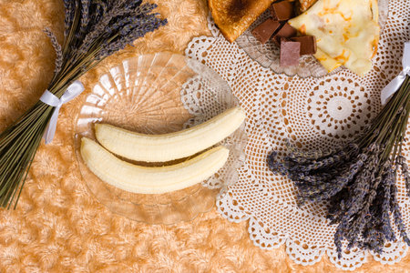Peeled bananas, crepes, chocolate, and lavender on a textured surface.の写真素材