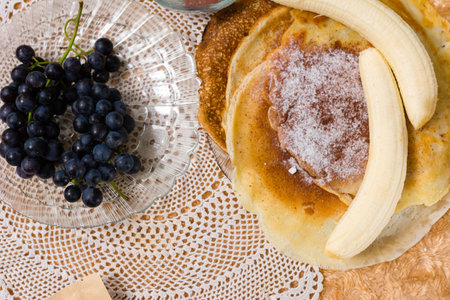 Pancakes with banana and powdered sugar, grapes on the side.