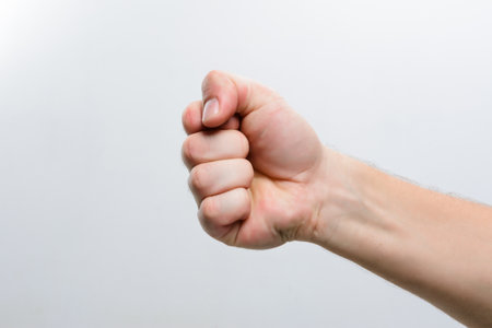 A person's hand is shown making a fist against a simple, light backdrop, highlighting the gesture.の写真素材