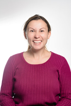 A middle-aged woman with brown hair and a maroon sweater smiles excitedly against a white background.の写真素材