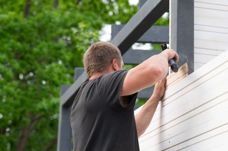 Installing and aligning boards in grooves when installing a wall in a gazebo, construction work and moments during the construction of a gazebo.の写真素材