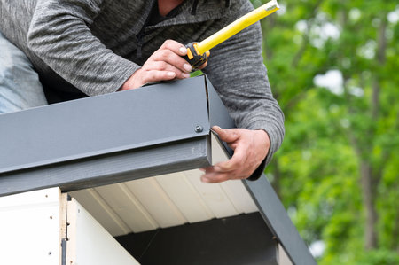 The craftsman measures the length of the metal cladding on the edge of the roof, construction work.