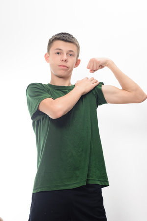 A portrait of a young man in a green shirt flexing his arm. He displays a confident expression. The image is clean and simple, ideal for health or fitness concepts.の写真素材
