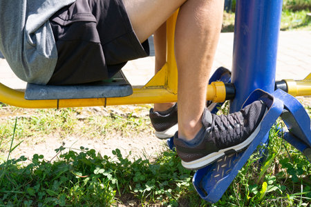 Person exercising on outdoor fitness equipment, strengthening legs.の写真素材
