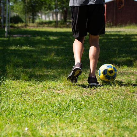 Person walking away with soccer ball on grassy fieldの写真素材