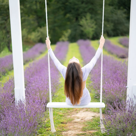 Woman relaxing on a swing in a lavender field. Serenity and peace in nature.の写真素材