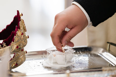 Close-up of a hand delicately placing a gold band into a transparent case. The scene suggests a...