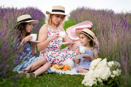 A heartwarming scene of a family enjoying a peaceful picnic in a vibrant lavender field. Mothers and...