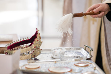 Close-up of a golden crown and a person pouring holy water during a religious ritual. The scene is solemn and symbolic, representing faith and tradition.の写真素材