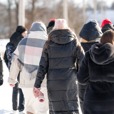 Winter stroll: People bundled up walking outdoors on a cold, sunny day.の写真素材