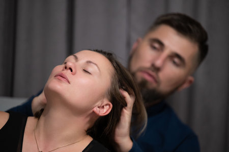 A man gently massages a woman's hair as she leans back in relaxation, enjoying a tranquil moment together in a softly lit room, with calming vibes enveloping them bothの写真素材