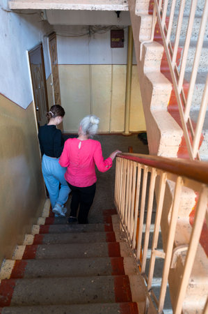 Two individuals descend a well-worn staircase in a familiar apartment building, fostering a bond with each step while enjoying the gentle embrace of the evening.の写真素材
