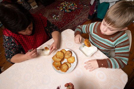 Two people savoring freshly made snacks at a table adorned with a lace tablecloth. The warm atmosphere radiates joy and togetherness, enhancing the culinary experience.の写真素材