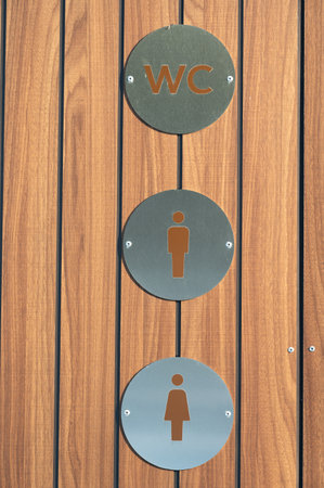 Restroom indicators showcase a stylish wooden backdrop with clear symbols for men's and women's facilities, emphasizing modern design and clear communication in a public area.の写真素材