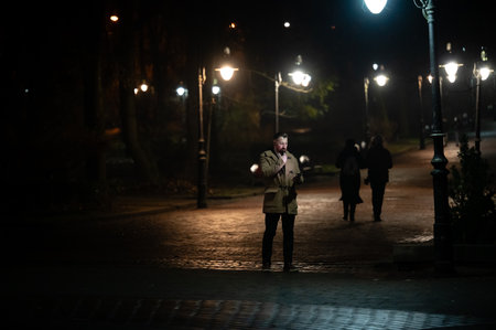 Evening wanderers meander along a cobblestone path, illuminated by glowing street lamps, creating a cozy, inviting atmosphere for nighttime strolls.の写真素材