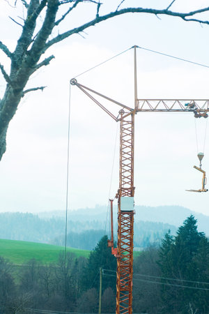 A construction crane towers over misty hills and trees, showcasing the fusion of nature and industry as work progresses on a new project.の写真素材