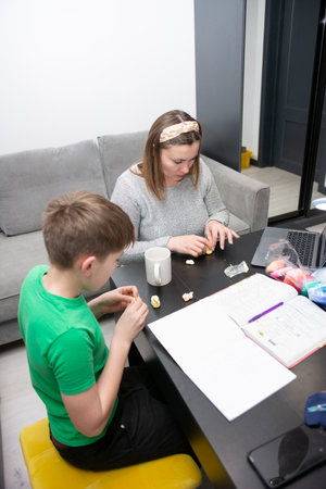 A mother and son enjoy quality time together, crafting with colorful clay at their dining table on a relaxed day indoors, fostering creativity and connection.の写真素材
