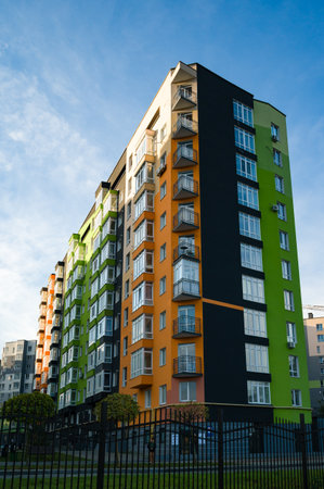 Colorful residential buildings rise elegantly against a brilliant sky, with hues of green, orange, and black bringing life to the urban landscape as families enjoy their day.の写真素材