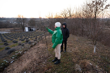 Two individuals focus on nurturing young trees, highlighting winter gardening practices while...