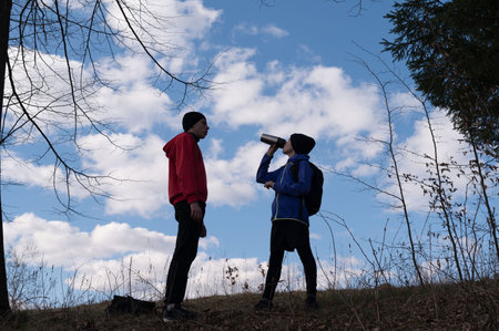 Two young adults, dressed in athletic wear, stand against a backdrop of a bright blue sky and...