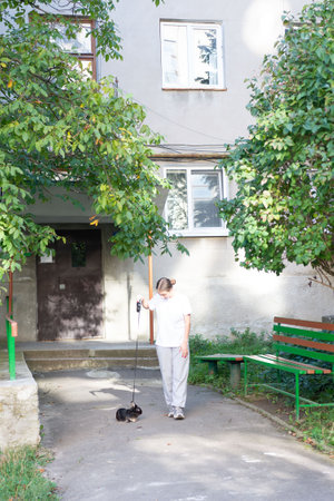 A young woman strolls with her pet rabbit on a leash near a residential building. Sunlight illuminates the scene, creating a peaceful atmosphere.の写真素材