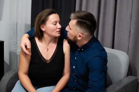 A couple is engaged in a tender gaze, seated closely together in their cozy living room, exuding warmth and connection. The ambiance is soft and inviting.の写真素材