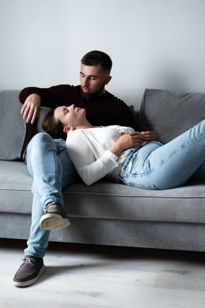 A couple enjoys a quiet afternoon on a comfortable couch, sharing affection and tenderness as they unwind in a cozy and inviting living room atmosphere.の写真素材