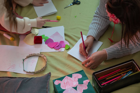 Two individuals collaborate on an arts and crafts project, crafting cards adorned with hearts and other decorations. The scene is warm and intimate, emphasizing creativity and connection.の写真素材