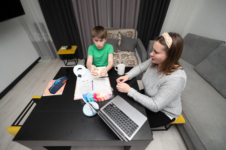 A child and an adult are engaged in a vibrant crafting activity at a modern table, focusing on creativity and teamwork during a cozy afternoon in a well lit living space.の写真素材