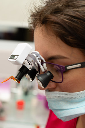 A skilled professional examines a specimen using specialized eyewear with magnification lenses, demonstrating dedication and focus in a scientific environment.の写真素材
