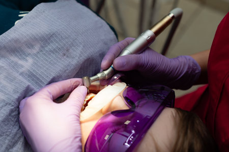 Patient relaxes under a purple light shield while a skilled dentist uses a laser tool for precision...