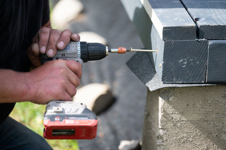 A man drills screws into wooden beams, working with wood.の写真素材