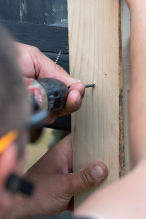 Screwing a board with a screwdriver, installing a wooden gazebo, carpentry work with wood.の写真素材