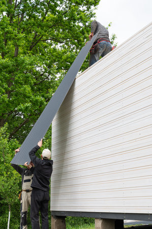 The moment of installation and construction of the roof of a wooden gazebo in the garden, a large gazebo with a closed room.の写真素材