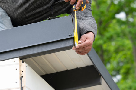 The craftsman measures the length of the metal cladding on the edge of the roof, construction work.の写真素材