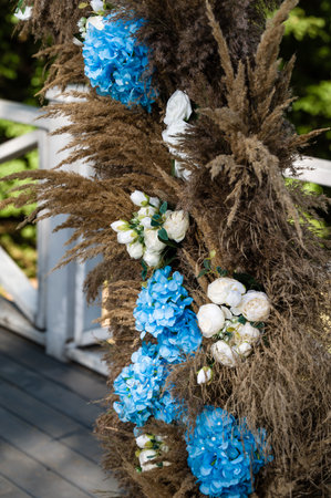 A stunning floral arrangement featuring blue hydrangeas and white roses, accented by dried pampas grass. Ideal for outdoor ceremonies or special occasions.の写真素材