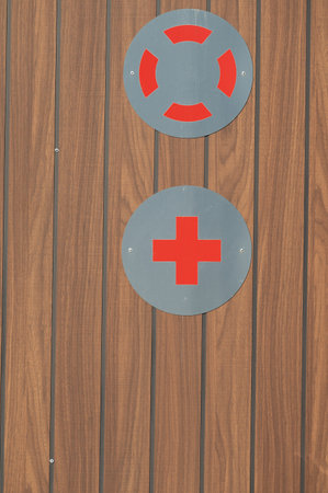 Two striking red symbols are mounted on a wooden wall, one resembling a lifebuoy and the other a...